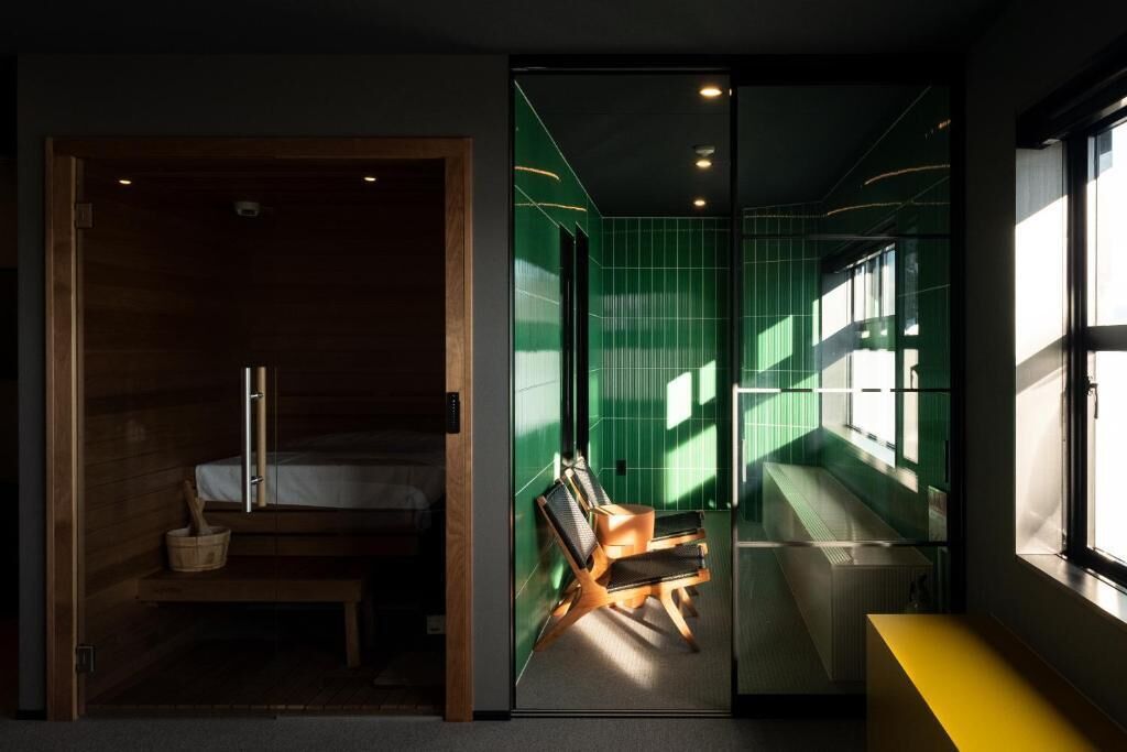 Ein modernes Hotelzimmer mit einem Bett, einem Sessel und Blick durch eine Glastür.