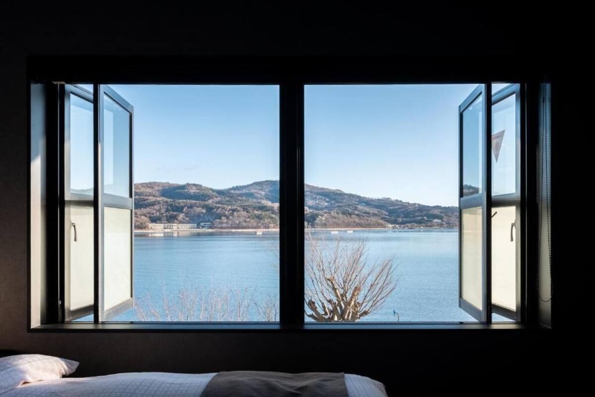 Una habitación con un gran ventanal que ofrece vistas a un lago y colinas.