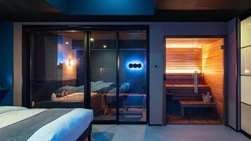 Quarto de hotel moderno com cama, área de estar e sauna.