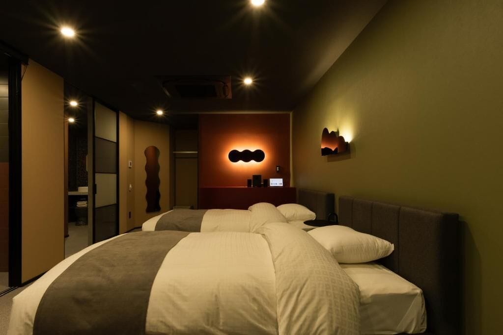 A hotel room with a large bed, a bedside table, a wall-mounted light, and a mirror.
