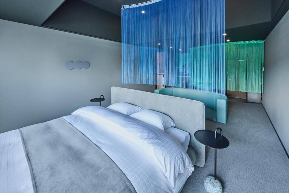 Un dormitorio moderno con cama, mesitas de noche y una cortina azul colgada.