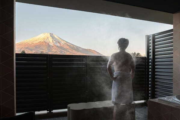 A person in a towel standing by a steam shower with a view of a mountain. - Mt Fuji View and Sauna Ryokan Shizuku (Yamanakako)