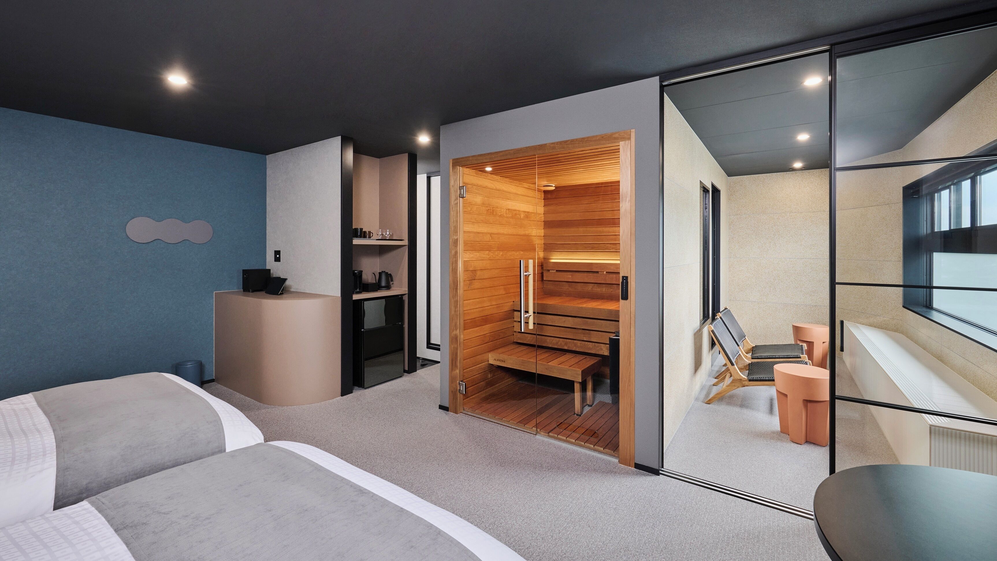 Une chambre d’hôtel moderne équipée d’un lit, d’un bureau, d’un coin salon et d’un sauna.