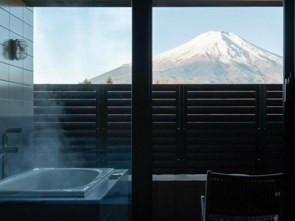 A bathroom with a hot tub and a view of a snow-capped mountain.