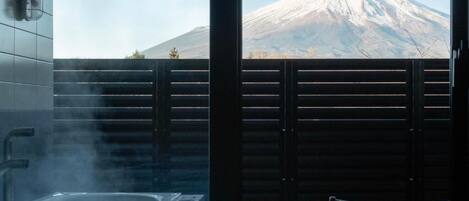 A bathroom with a hot tub and a view of a snow-capped mountain.