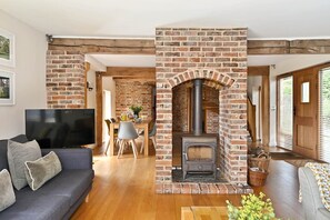A living room with a TV, sofa, and fireplace. - Hare Farm Oast - amazing views - ideal for family celebrations (Rye)