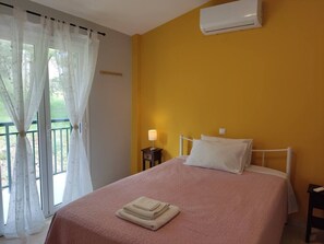 Ein Schlafzimmer mit einem Bett, einem Nachttisch, einer Lampe und einer Klimaanlage.