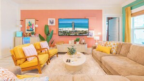 Una sala de estar con un sofá, sillones, una mesa de centro y un televisor montado en la pared.