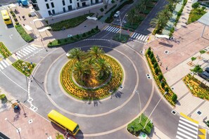 A roundabout with palm trees and a central landscaped area. - Bloomfields 1BR in Water's Edge 2-Yas Island (Abu Dhabi)