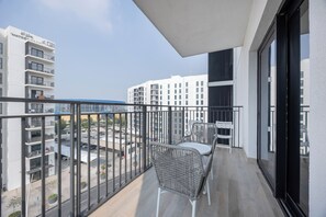A balcony with a view of a cityscape, featuring modern buildings and a parking area. - Bloomfields 1BR in Water's Edge 2-Yas Island (Abu Dhabi)