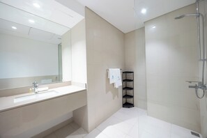 A modern bathroom with a large mirror, a sink, and a shower. - Bloomfields 1BR in Water's Edge 2-Yas Island (Abu Dhabi)