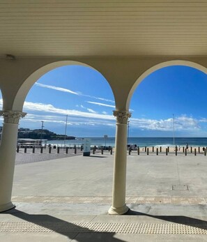 A covered walkway with columns, leading to a beach area with a clear view of the sea. - Luxury Apartment Bellevue Hill walk to Bondi Beach (Bellevue Hill)