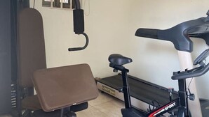 Ein Fitnessraum mit einem Ergometer, einer Bank und einem Laufband.