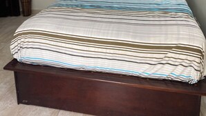 Ein Schlafzimmer mit Bett, Vorhängen, einer Topfpflanze und einer Klimaanlage.