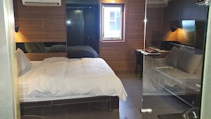 Une chambre d’hôtel avec un lit, un bureau, une chaise, un miroir et une fenêtre.