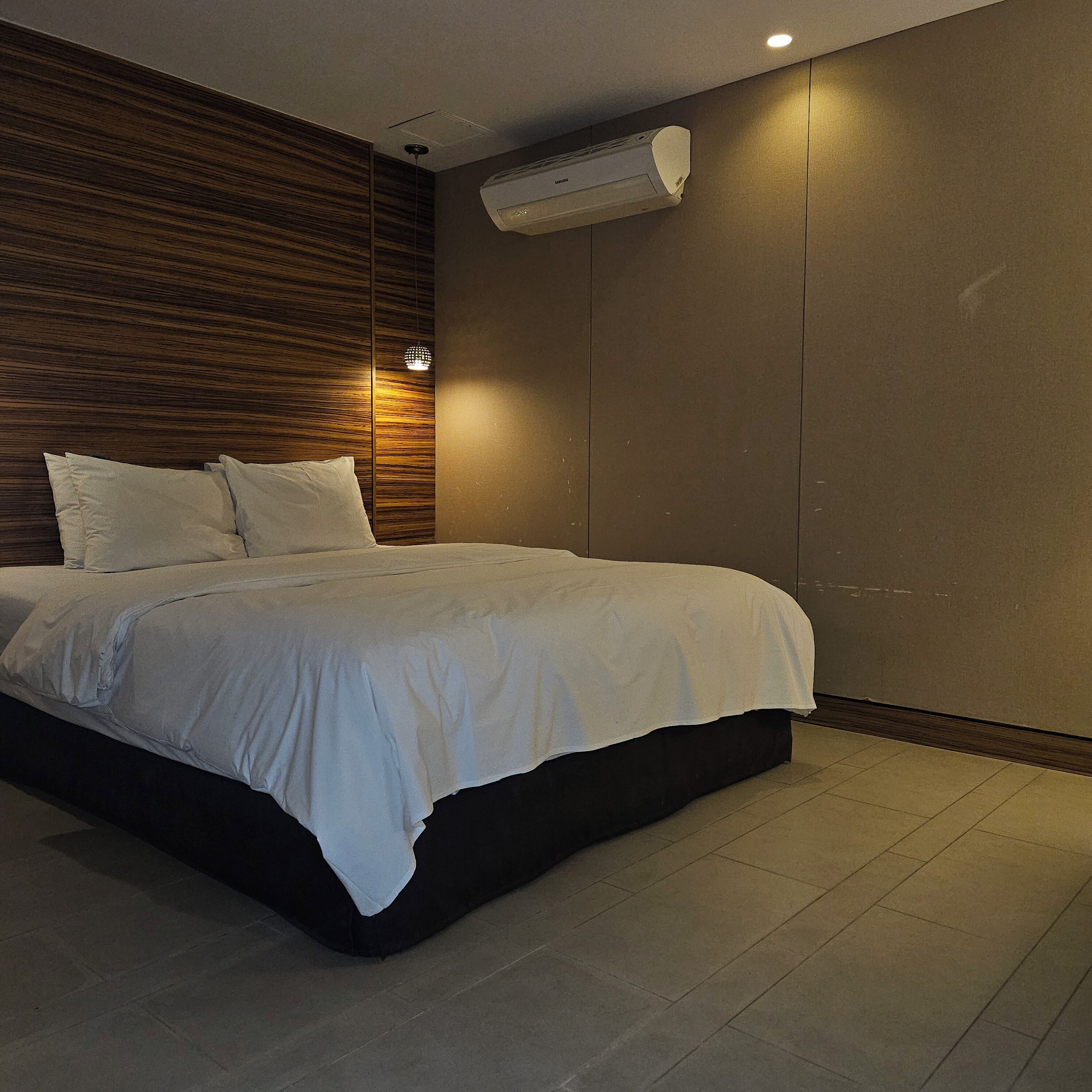 Une chambre moderne avec un lit, un mur recouvert de panneaux en bois et un appareil de climatisation.