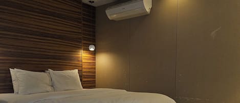Une chambre moderne avec un lit, un mur recouvert de panneaux en bois et un appareil de climatisation.