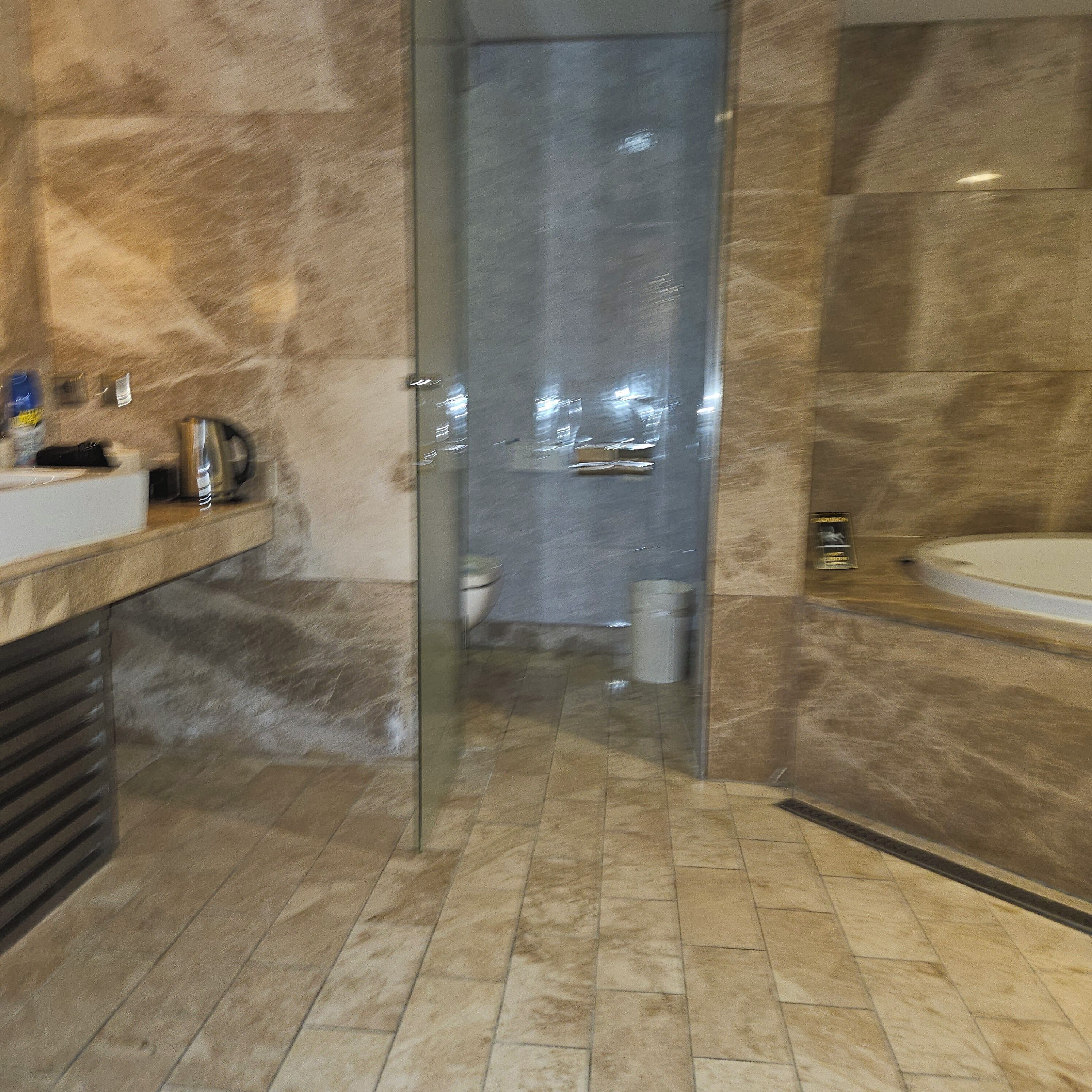 A modern bathroom with a glass shower door, a bathtub, and a vanity with a sink.