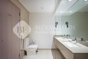 Un baño moderno con inodoro, bidé y dos lavamanos.