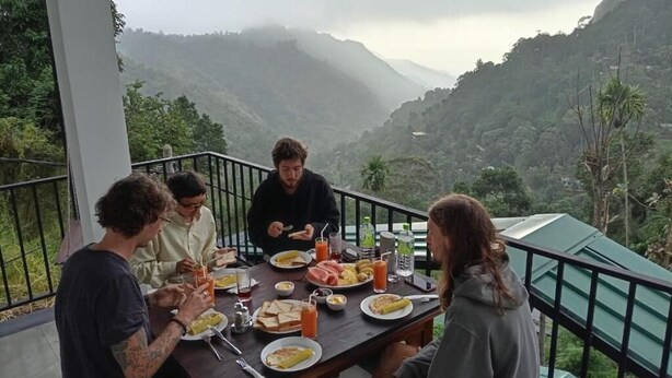 A group of people dining at an outdoor table with a mountain view. - Elite Ella (Ella)