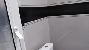 A compact, modern bathroom with a white toilet and a glass door. - Elite Ella (Ella)