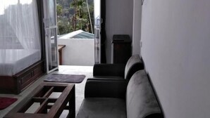 A modern living room with a sofa, a coffee table, and a sliding glass door leading to a balcony with a view of palm trees. - Elite Ella (Ella)
