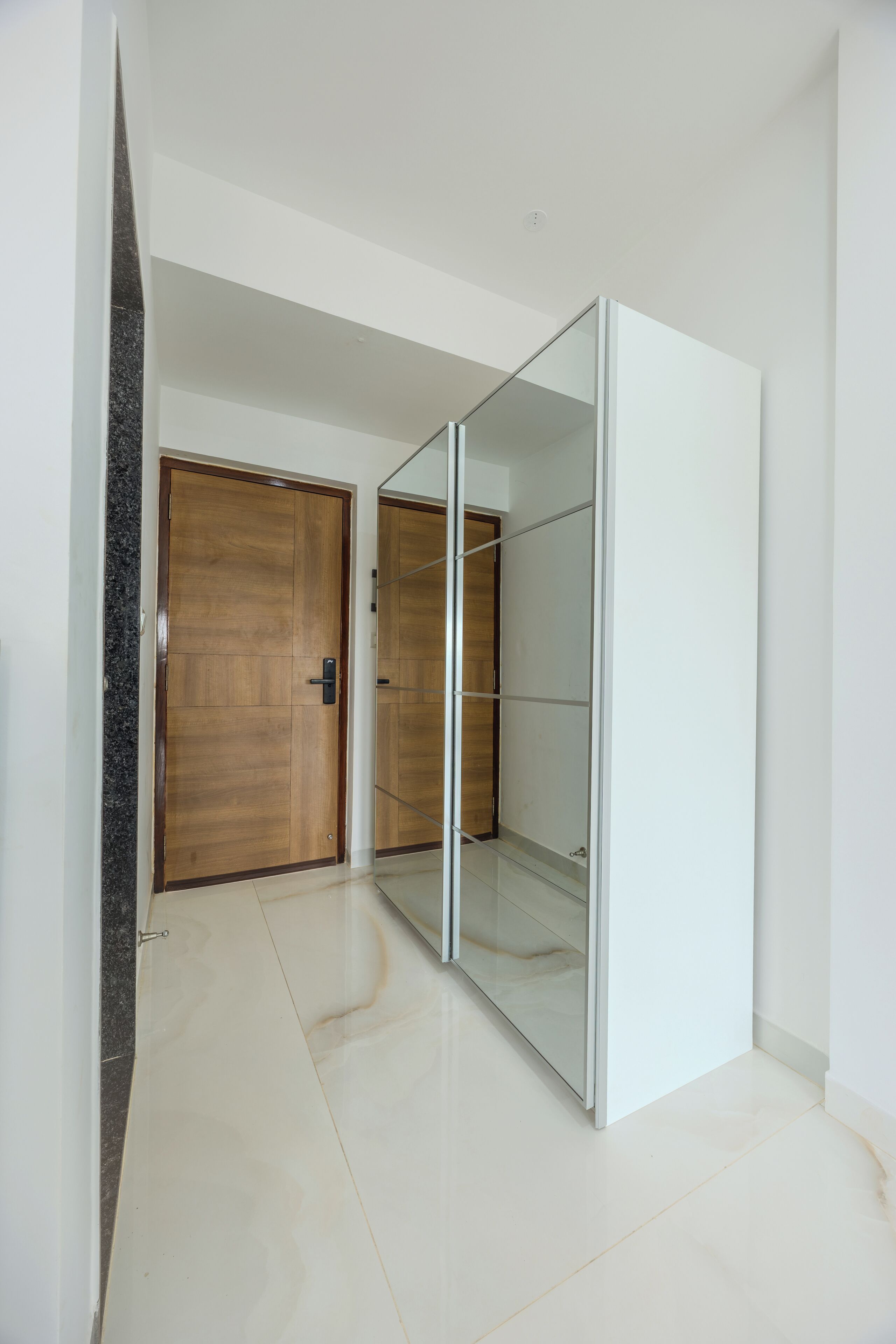 A hallway with a wooden door and a mirrored closet.