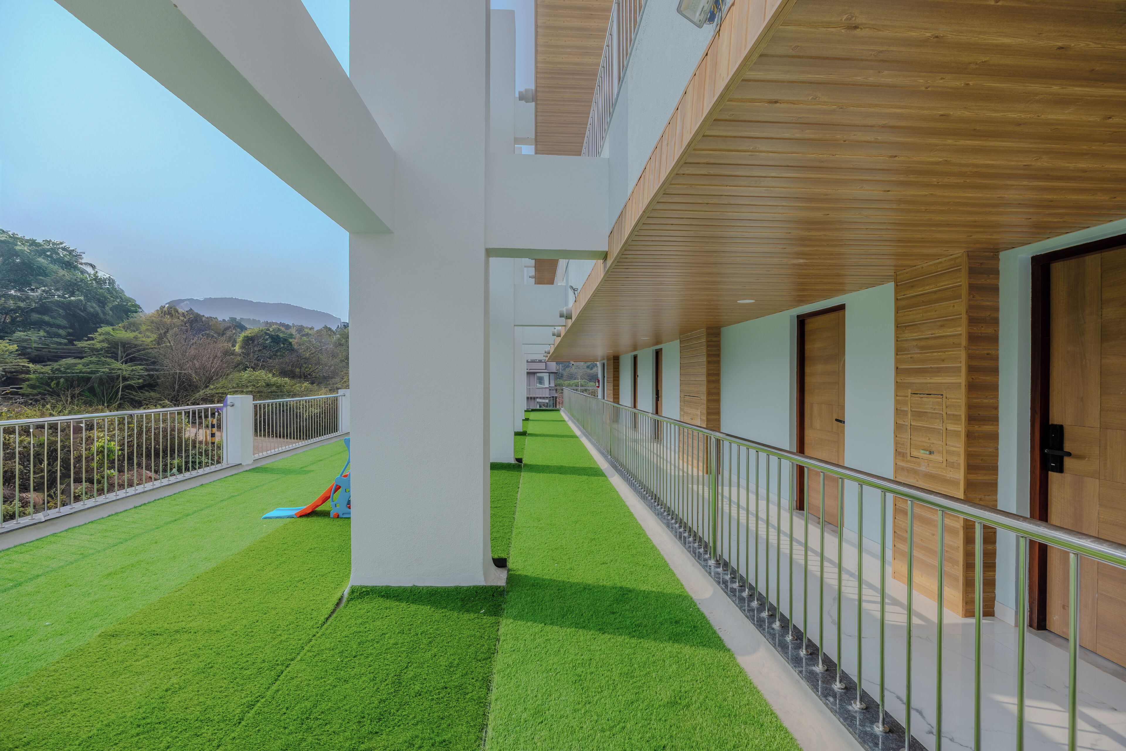 Un pasillo con césped artificial verde, techo de madera y barandillas de metal.