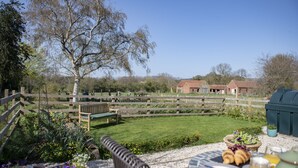 A patio with a table set for breakfast, a wooden fence, and a grassy area with trees. - Green Balk Cottage, Great Broughton, Yorkshire (Stokesley)