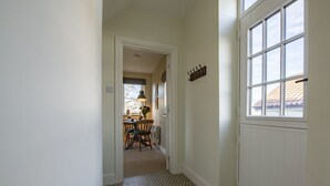 A hallway with patterned flooring leading to a dining area with a table and chairs. - Green Balk Cottage, Great Broughton, Yorkshire (Stokesley)