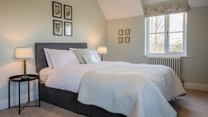 A bedroom with a bed, two bedside tables, a window, and wall art. - Green Balk Cottage, Great Broughton, Yorkshire (Stokesley)