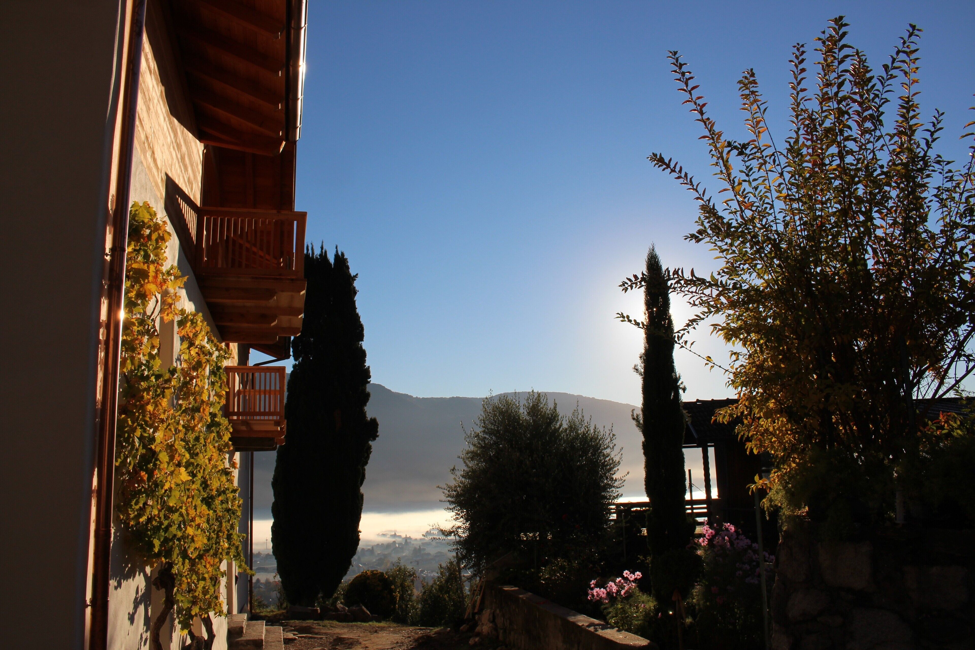 Un patio con balcón de madera, pared de piedra y vistas a la montaña.