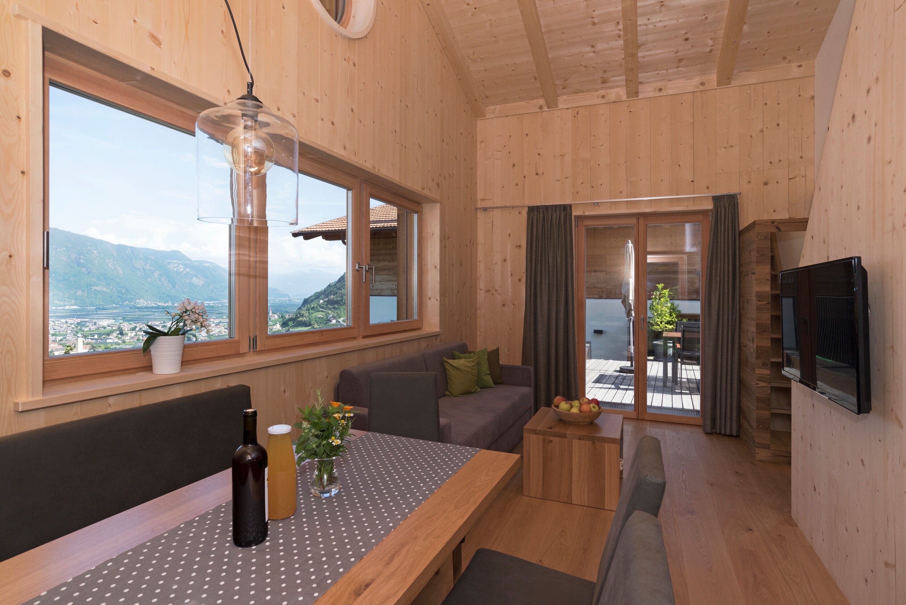 Ein Holzinnenraum mit Esstisch, Sofa und Fernseher.