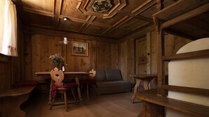 Ein Holzinnenraum mit Esstisch, Stühlen, einer Couch und einem Kamin.