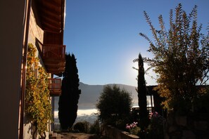 Une cour avec un balcon en bois, un mur de pierre et une vue sur une montagne.