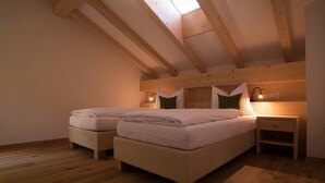 Ein Schlafzimmer mit zwei Betten, Holzbalken, einem Oberlicht, Nachttischlampen und einem Nachttisch.