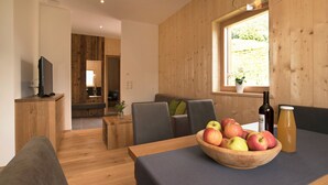 Ein modernes Interieur mit einem Esstisch, Holzwänden, einem Fenster mit Aussicht und einer Schale mit Obst.