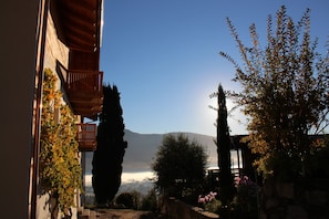 A courtyard with a wooden balcony, a stone wall, and a view of a mountain. - Apartment 'Greiterhof Weingarten' with Mountain View and Wi-Fi (Lana)