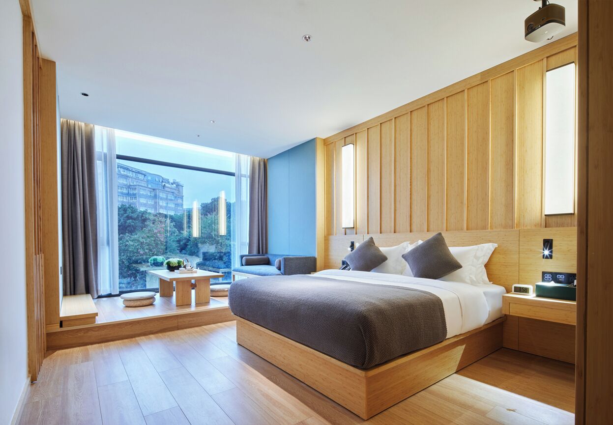 Un dormitorio moderno con una cama grande, una mesita y vistas a la ciudad.