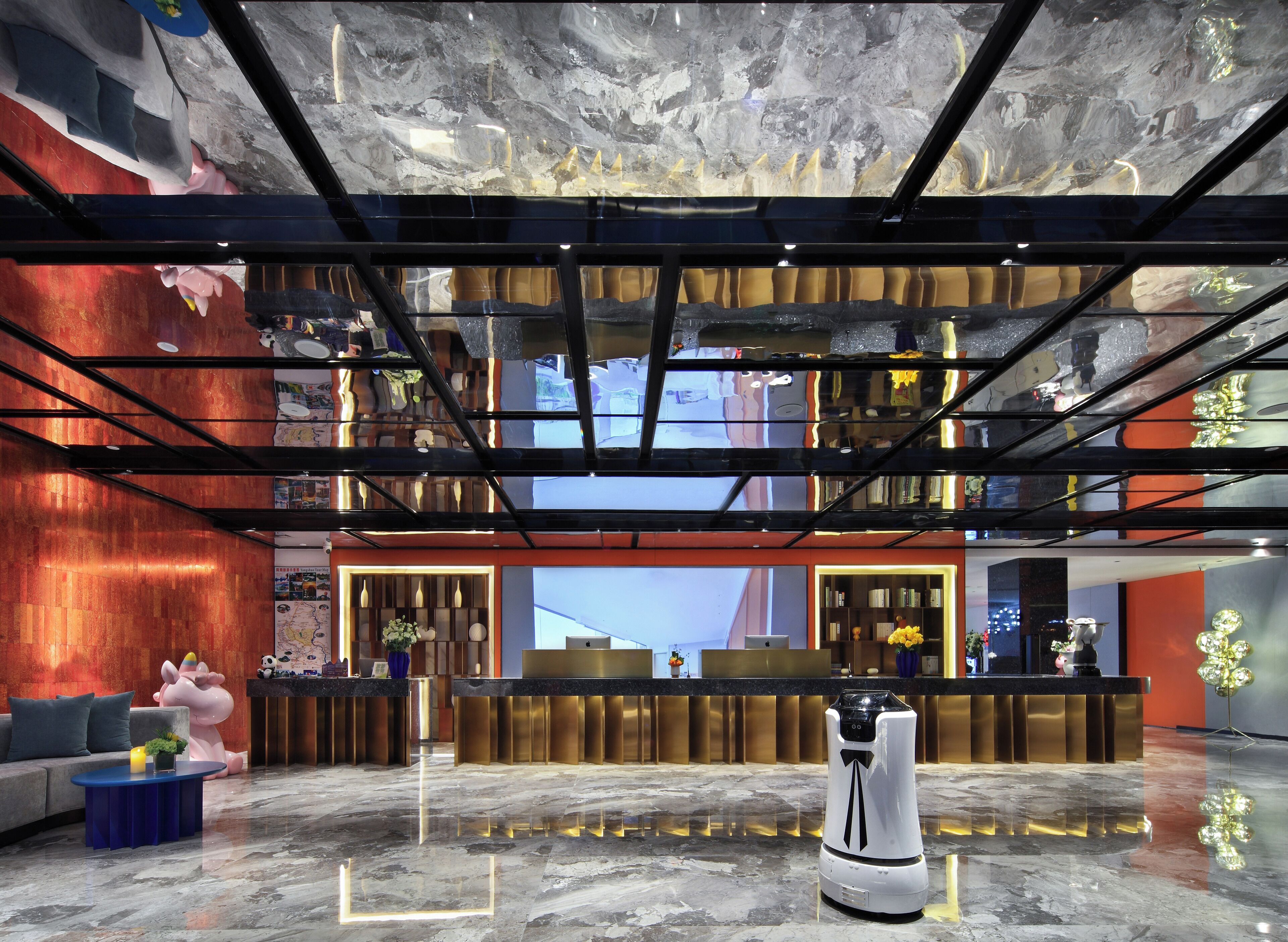A modern lobby with a reception desk, seating area, and a robot.