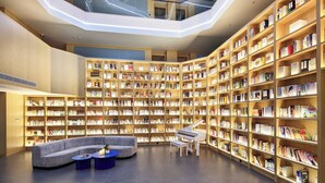 Una biblioteca moderna con varios niveles, estanterías y zonas de estar.