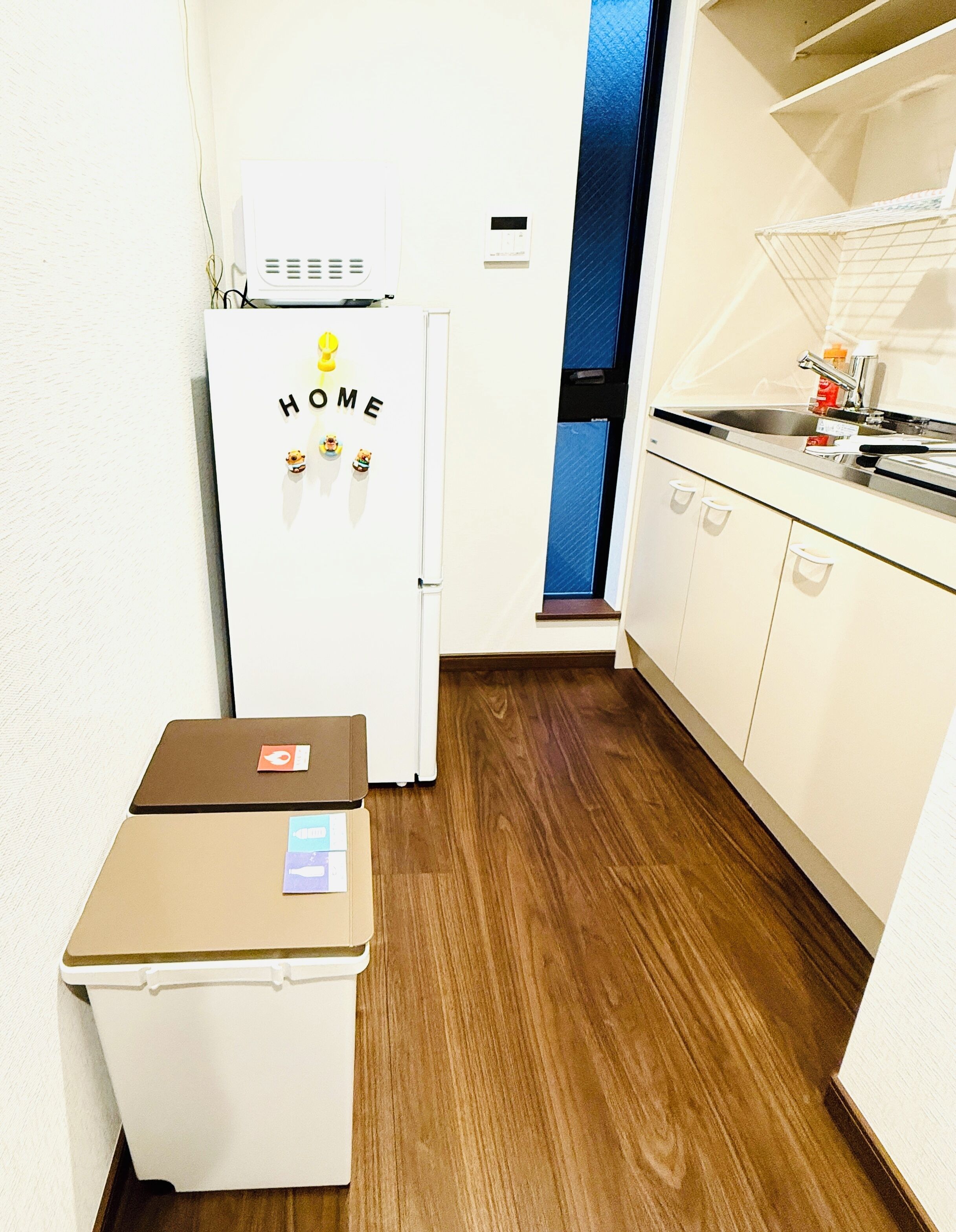 A compact kitchen with a refrigerator, a small countertop, and a wooden floor.