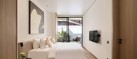 Quarto moderno com cama grande, televisão de tela plana e varanda com área de estar ao ar livre.