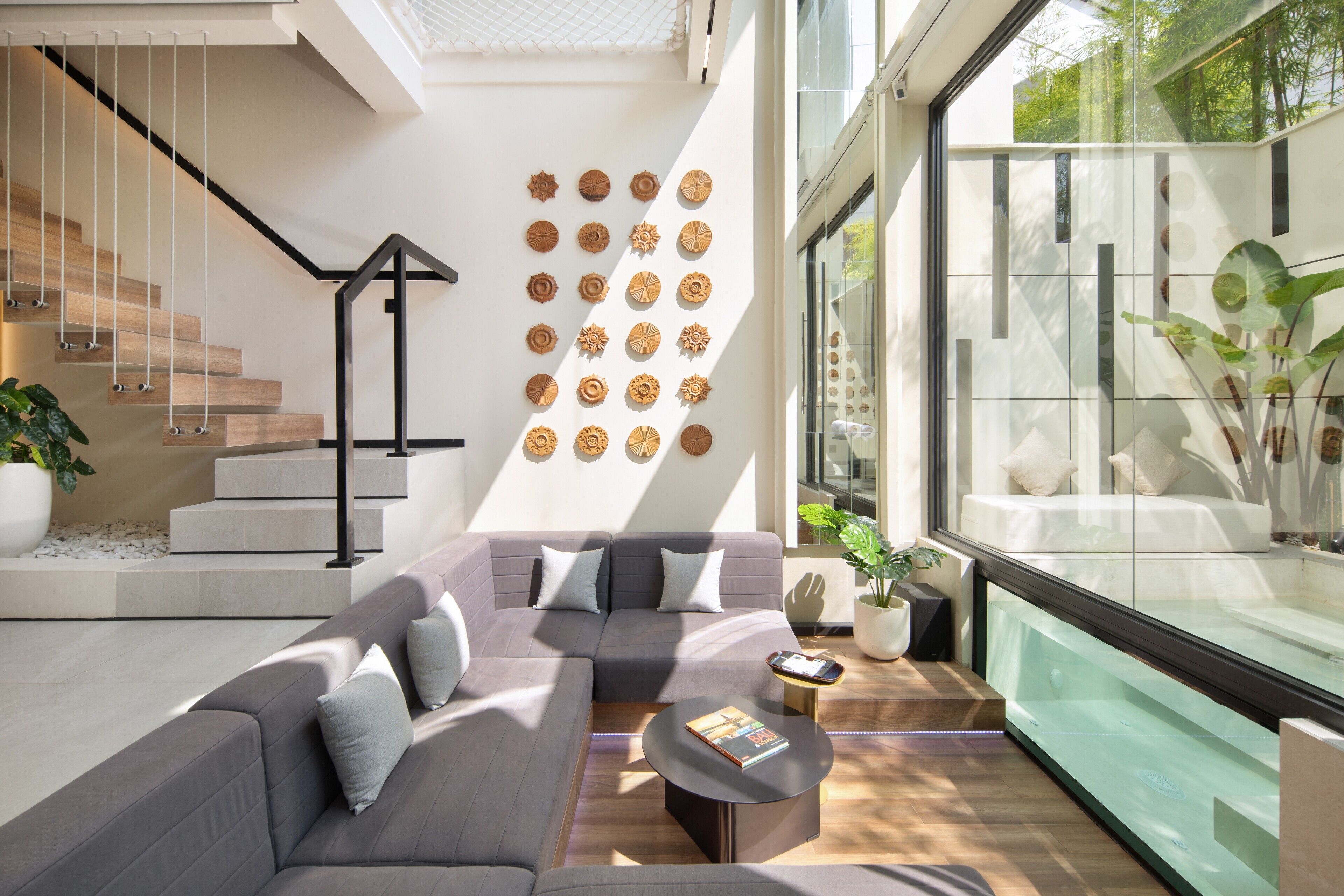 A modern living room with a grey sectional sofa, a round coffee table, and a staircase with wooden steps.