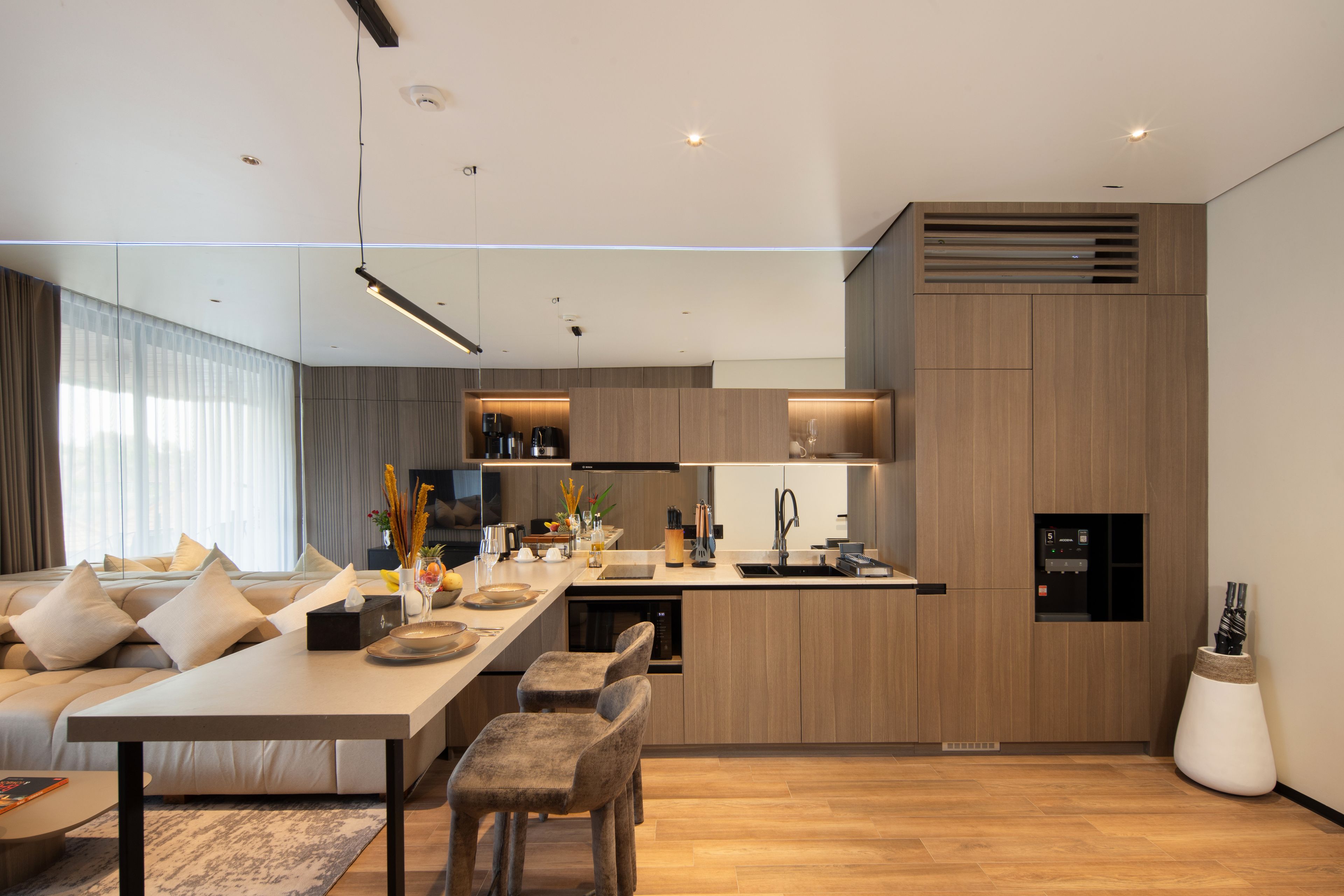 A modern kitchen with a central island, built-in appliances, and a dining area with a sofa and chairs.