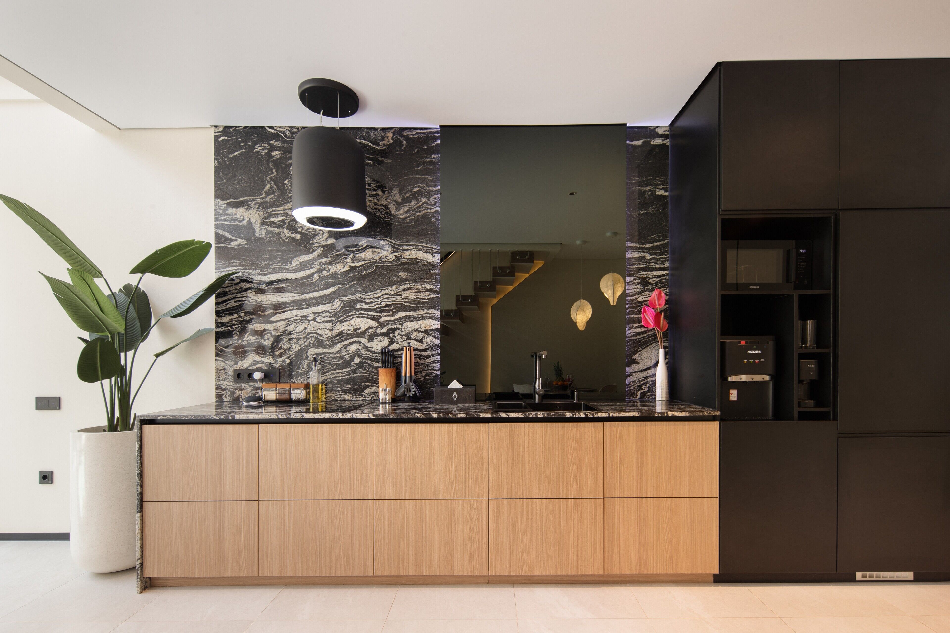 A modern kitchen with a marble backsplash, wooden cabinets, and a built-in microwave.
