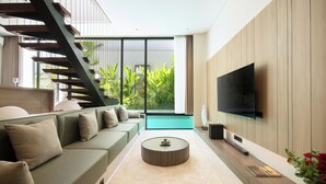 Una sala de estar moderna con una escalera, un televisor de pantalla plana grande, un sofá verde y una mesa de centro.