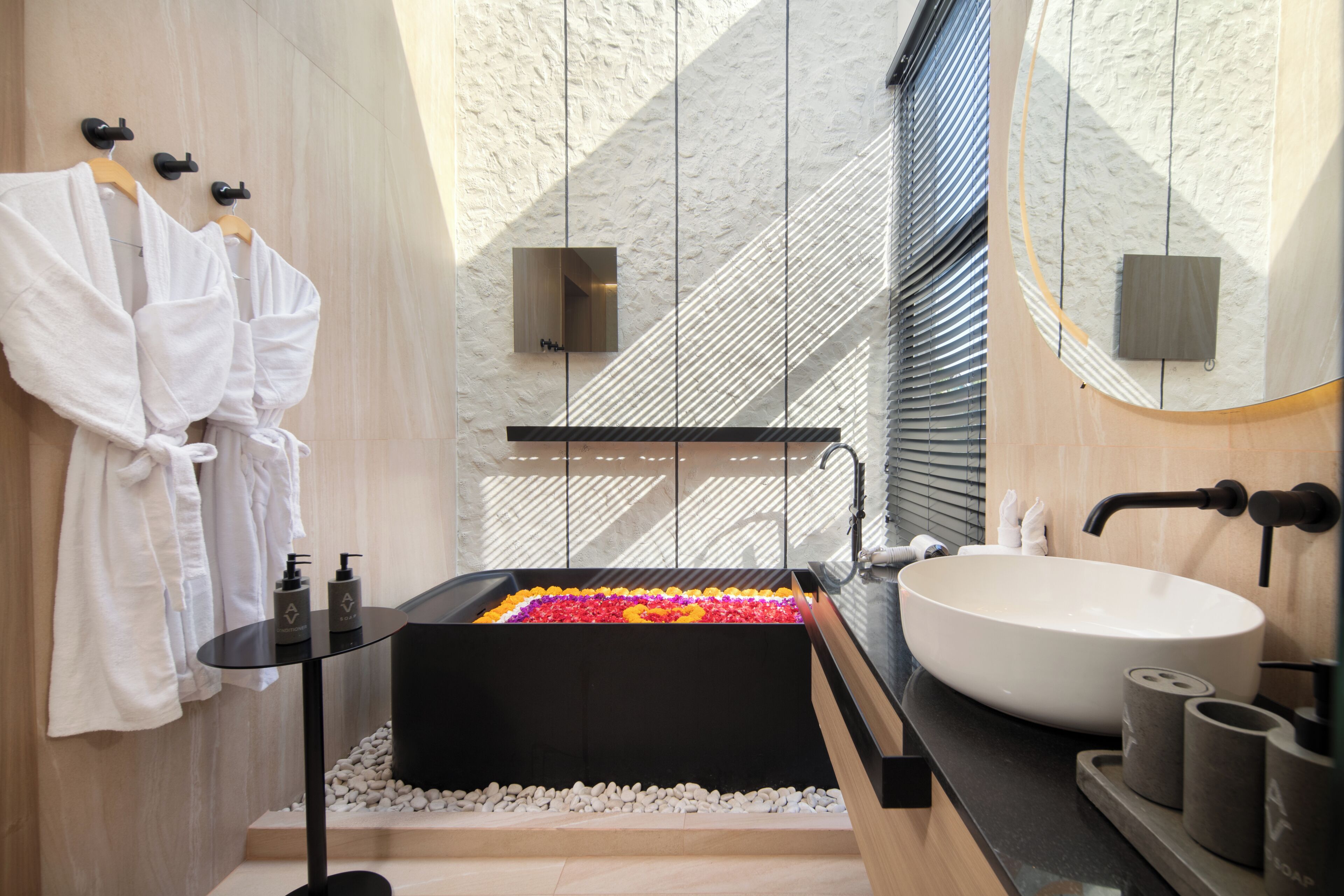 Een moderne badkamer met een groot ligbad, witte handdoeken en een ruime spiegel.