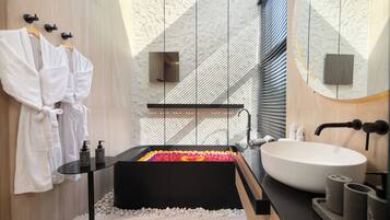 Een moderne badkamer met een groot ligbad, witte handdoeken en een ruime spiegel.