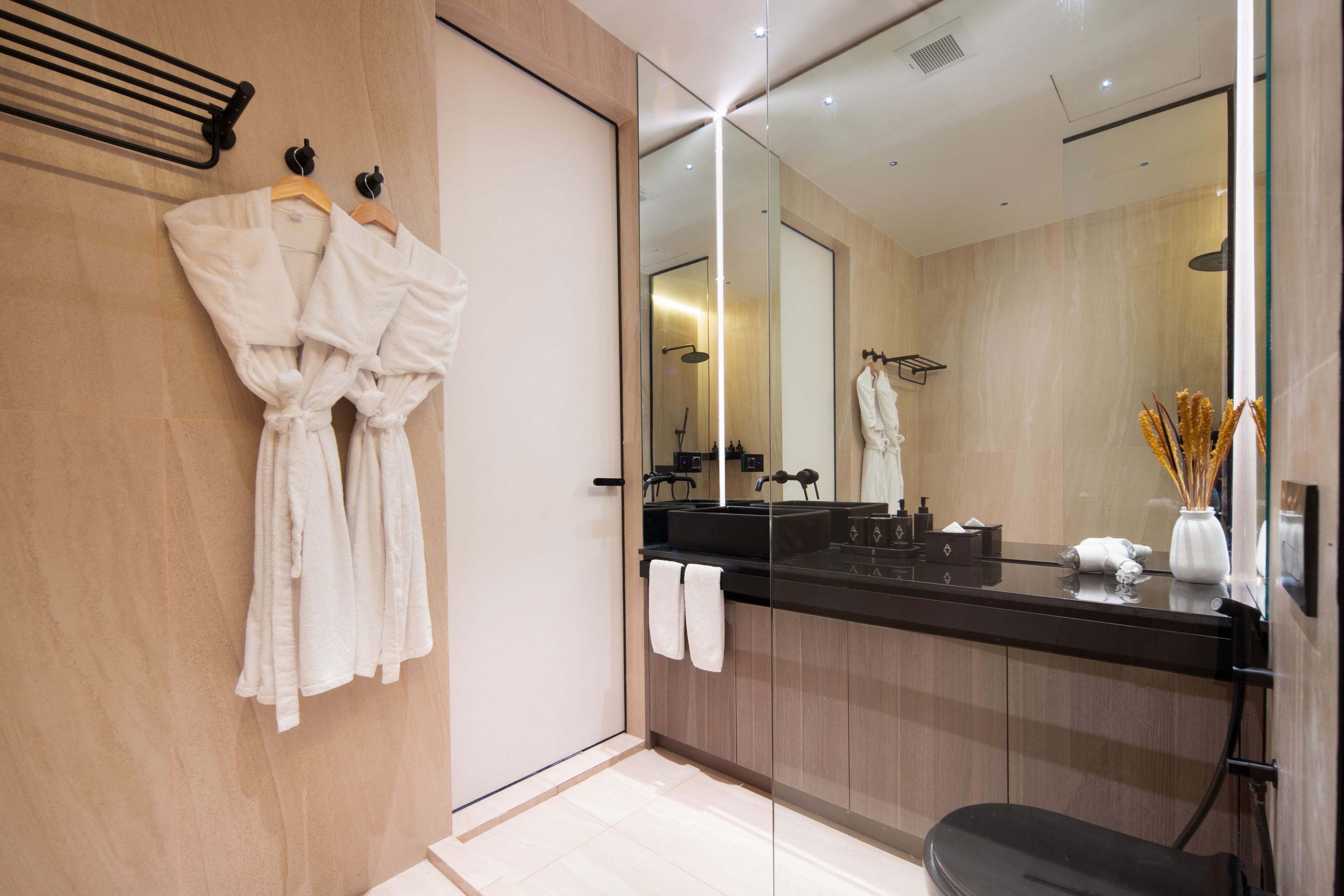 Une salle de bain moderne avec un grand miroir, un comptoir noir et deux serviettes blanches.